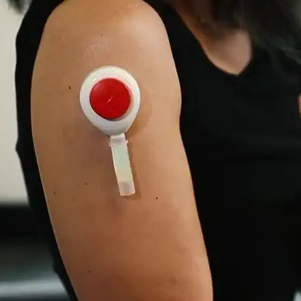 The Heyday collection device pressed against an upper arm, drawing a sample without a needle